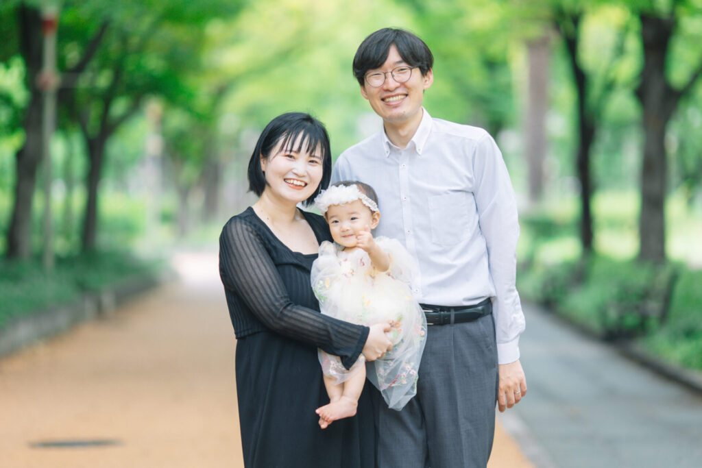 大阪の靱公園で笑顔で家族写真を撮影している家族 赤ちゃんが指を指している