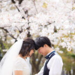 ウェディング姿で桜フォトウェディングをする新郎新婦