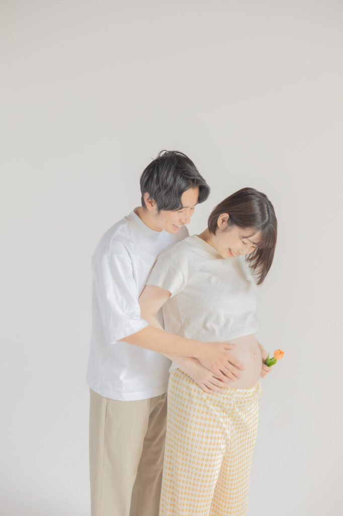 花を持ってマタニティフォトを撮影している新郎新婦