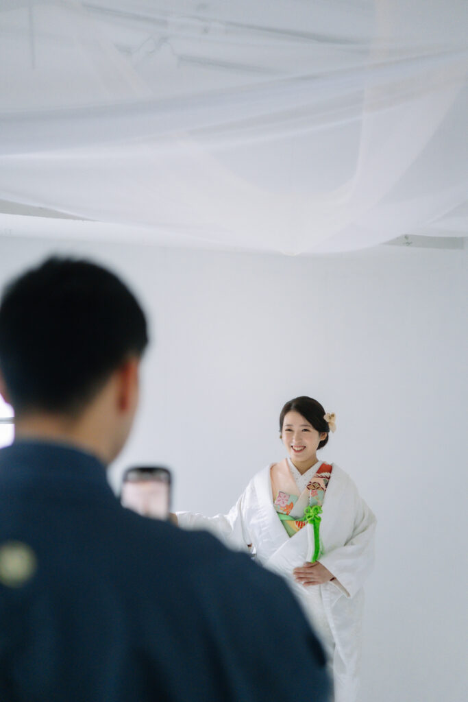 大阪のフォトウェディングで和装の新郎が自身のスマホで新婦を撮影しているシーン