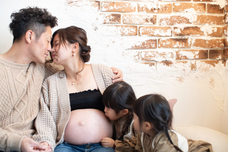 黒とやわらかなベージュのカーデの妊婦とグレーのタキシードで妊婦に寄り添う夫のマタニティフォト