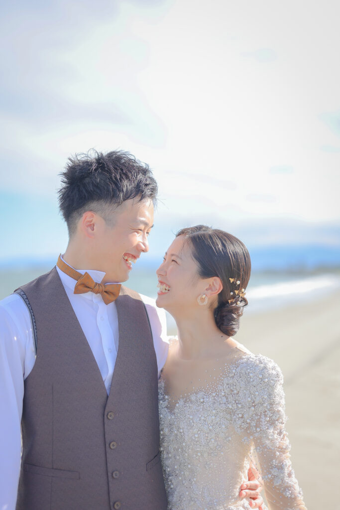 大阪フォトウェディングの海ロケーションで見つめ合いながら笑顔で撮影する新郎新婦