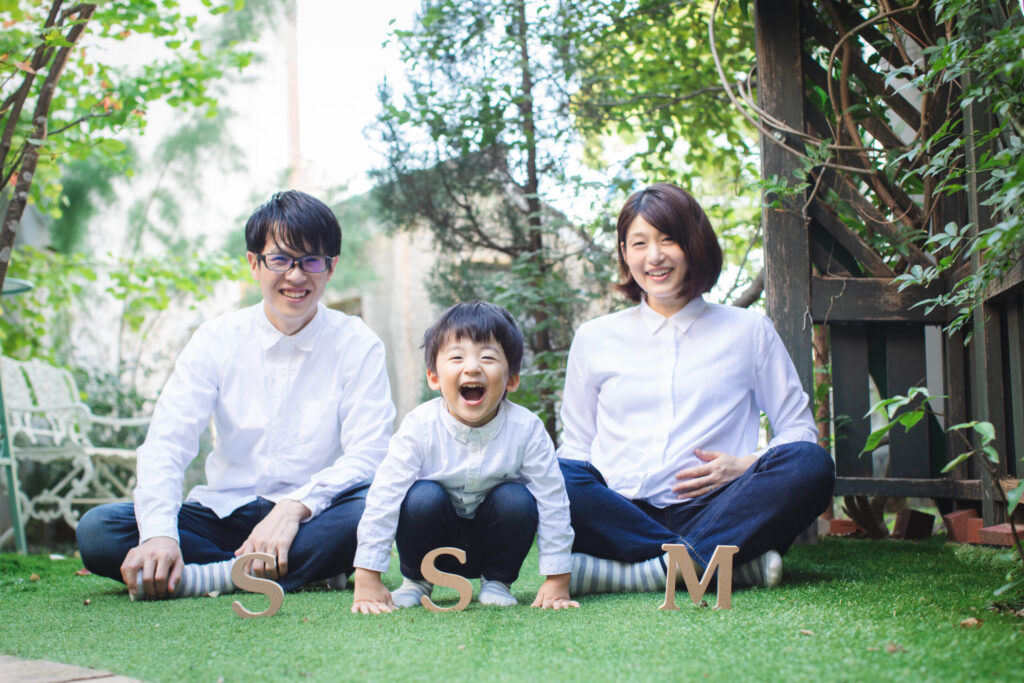 お揃いの白シャツで家族3人でマタニティフォトを撮影している様子