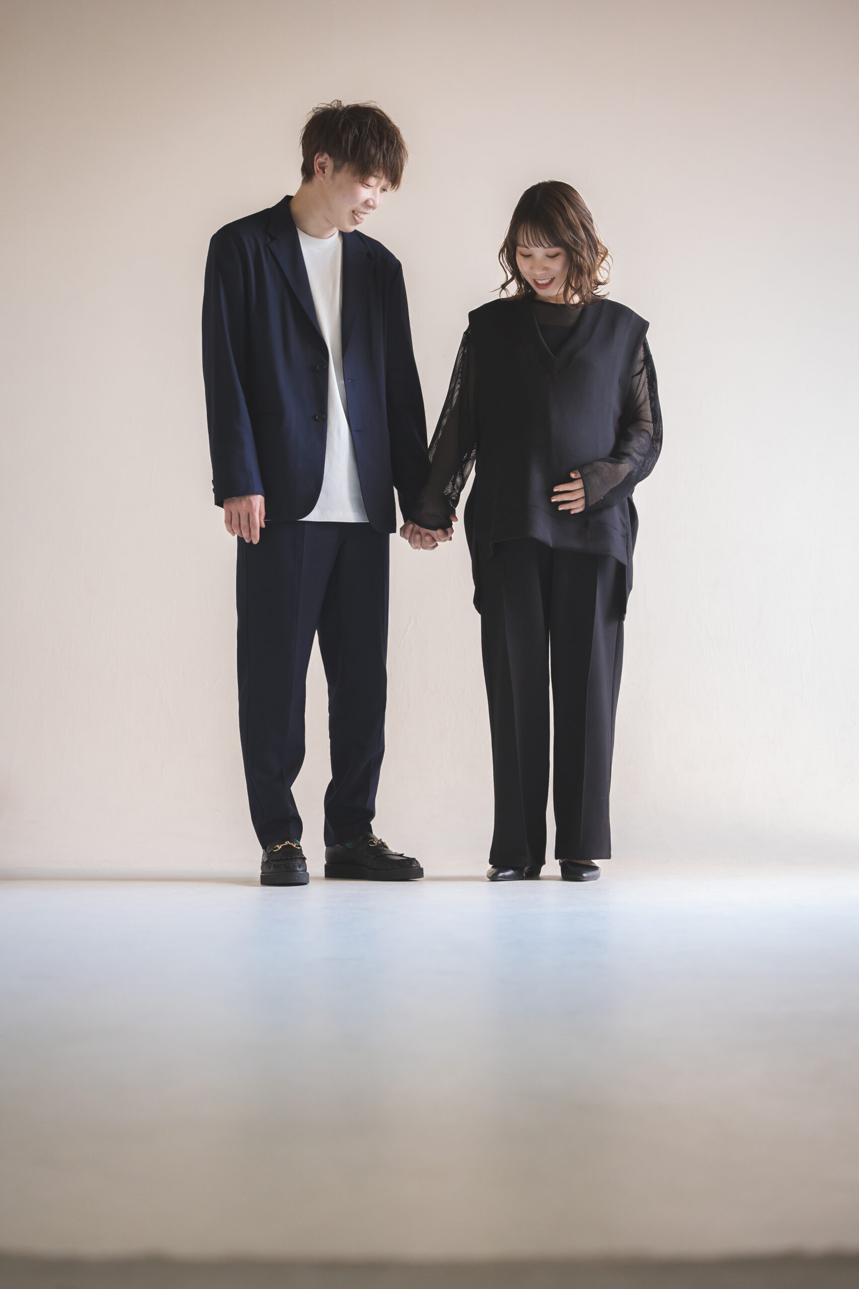 黒のセットアップパンツでマタニティフォトを撮影する妊婦さんと黒いジャケットを着た旦那さん