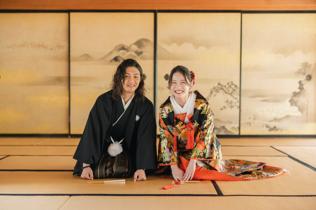 大阪フォトウェディングで和装姿の新郎新婦が三つ指をついて笑顔でカメラを見つめるシーン