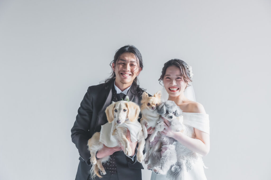 大阪のスタジオでウェディング姿の新郎新婦が犬を抱っこして微笑むフォトウェディングの1枚