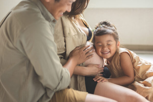 子供が母親のおなかに寄り添っているマタニティフォト